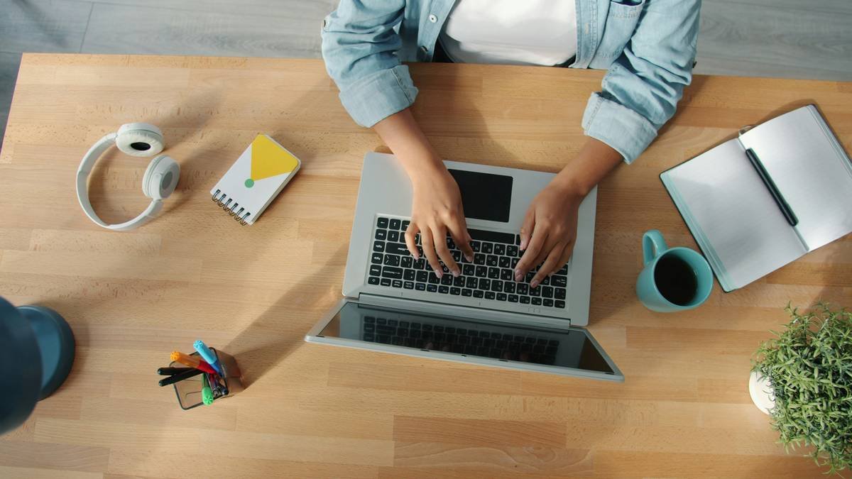 female freelancer typing working with laptop at wooden desk concentrated on activity. Modern devices and internet work concept.